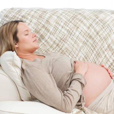 Gravid kvnnar vilar på soffa. 