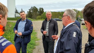 En grupp män diskuterar hur den estniska utbildningen av vindkraftverkstekniker kan arrangeras utomhus på ett lobbningsevenemang.