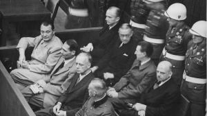 Hermann Göring, längst t.v. i främre raden, i samband med rättegången i Nürnberg. Göring dömdes till döden, men begick självmord med hjälp av en cyanidkapsel ett par timmar innan dödsstraffet skulle verkställas. Hermann Göring, Rudolf Hess m.fl. vid Nürnbergrättegången