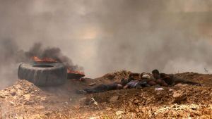 Palestinier tar skydd under sammandrabbningarna med israeliska soldater vid gränsstängslet.