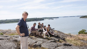 Miak Kaurismäki står på en klippa med skådespelarteamet bakom sig.