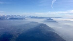 År 2018 var halterna av växthusgaser högre än medletalet de tidigare decennierna. Ökade haöter av växthusgaser i atmosfären så som koldioxid och metan bidrar negativt till klimatförändringen. De franska och schweiziska Alperna täcks delvis av moln och atmosfären ovanför ser kylig ut i solskenet.