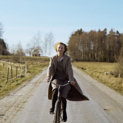 Den unga Astrid cyklar på landsvägen.
