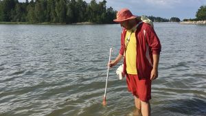 Tobias Lillqvist mäter vattentemperaturen och tar samtidigt en titt på algläget i Torsnäs badstrand i Hertonäs. Tobias Lillqvist mäter temperaturen i strandvattnet.