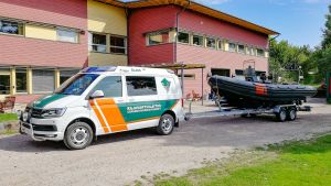 Sjöbevakarna drar sin ribbåt med en trailer till Lojosjön. Sjöbevakarnas båt på en trailer som dras av en paketbild.
