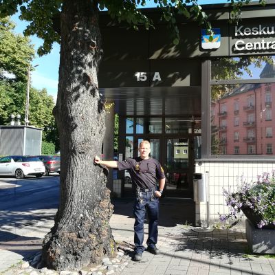 Brandmästare Vesa Berg står lutad mot ett trädd utanför Centralräddningsstationen i Berghäll.