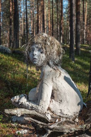 Eksynyt on Essi Korvan teos vuodelta 2012. Lapsenmuotoinen vaaleasta massasta muotoiltu patsas, hiukset sammalta, katsoo kuvasta vasemmalle, taustalla metsää