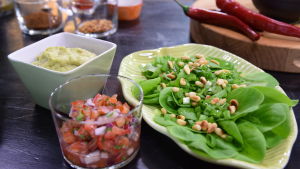 Valmista tomaattisalsaa, guacamolea ja vihreääsalaattia keittiössä.