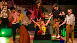 En flicka i gul skjorta kommer ut ur en kappsäck i en ungdomsshow i Pargas.