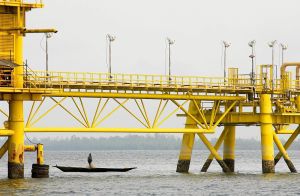 Nigeriansk fiskare i träbåt under en pipeline Nigeriansk fiskare i träbåt under pipeline