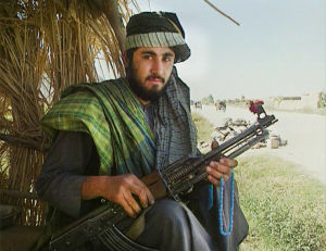Taliban-sotilaan aseen päähän kiinnitetty kukka luo rauhanomaisen vaikutelman Taleban dokumentissa Heroin Express (1995)