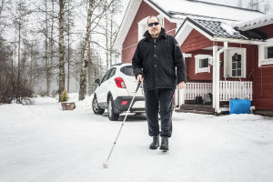 Markku Tallila valkoisen kepin kanssa kotipihallaan.