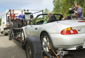 Yleisradion televisio-ohjelma komediasarja (draamasarja) "Rakastuin mä luuseriin". Ohjelman kuvaukset. Pakettiauto hinaa kuvaustraileria (kuvaustraileri), jonka perässä henkilöauto (kuvattavat näyttelijät autossa). Kuvaussuunnittelija Harri Halonen ja ohj