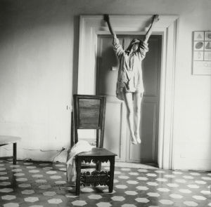 Francesca Woodman, nimetön, Rooma, Italia, 1977–78 Francesca Woodmanin teoskuvassa taiteilija roikkuu paitasillaan ovenkarmista ristiinnnaulittua muistuttavassa asennossa.