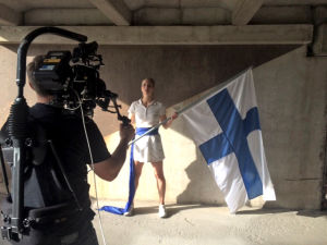 Nainen pitää suomenlippua tv-sarjan Urheilu-suomi kuvauksissa