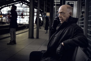 J.K. Simmons on Howard Silk Counterpart-sarjassa. Mies istuu asemalla.