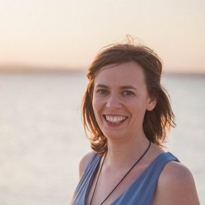 Sandra vet hur mycket turismen kan betyda för ett land. En kvinna med axellångt hår och en grön ärmlös blus. Hon står på en strand och i bakgrunden syns horisonten.