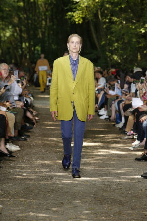 Muotimaailma on innostunut asuista, jollaisia suomalaismiehet ovat käyttäneet vuosikymmeniä. Tämä kokonaisuus on Balenciagan muotitalon kevätmallistosta. Balenciagan vuoden 2018 kevät malliston esittelykuva. Mies keltaisessa takissa.
