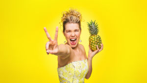 Tuija Pehkonen keltaisessa tilassa ananas kädessään.