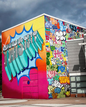 Åtta personer från grupperna Hende och Deos Ensemblen målade den här hyllningen till graffitins historia och nutiden. Verket har fått sitt namn från en klassikerfilm i hiphopkretsar, dokumentären Style Wars (1983) där graffitimålare för första gången ser sina målningar på förbipasserande tågvagnar: “This is it! This is it!”, ropar de. Beställningen av det här verket är en historia i sig, och den ska vi ännu återkomma till. Teksti This is it! monivärisessä grafffititeoksessa Vantaan taidemuseon Artsin ulkoseinässä Myyrmäessä.