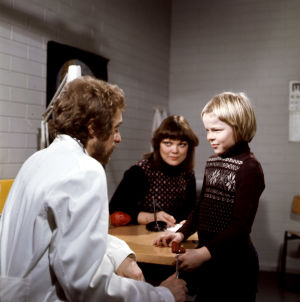 Timo (Kyösti Väntänen) lääkärin (Esa Pakarinen junior) vastaanotolla, taustalla opettaja (Pirkkoliisa Tikka) Villahousupakko-elokuvassa 1977 Villahousupakko-elokuvassa 1977 Timo (Kyösti Väntänen) lääkärin (Esa Pakarinen junior) vastaanotolla, taustalla opettaja (Pirkkoliisa Tikka)