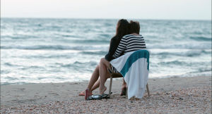 Margarita Mamun istuu rannalla naisen sylissä ja katselee merta