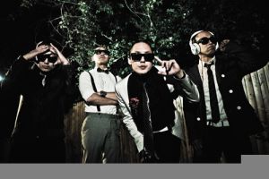 Far East Movementin nelikko poseeraa illan pimeydessä ulkona puuaitaa vasten // Kuva: www.fareastmovement.com