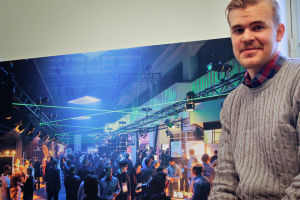 Riku Mäkelän taustalla on kuva vuoden 2013 Slushista. Se oli viimeinen kerta, kun tapahtuma järjestettiin Kaapelitehtaalla // Kuva: YleX / Jussi Latvala