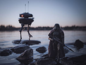 Är det på riktigt eller är det verkligen leksaker? En leksaksfigur föreställande en soldat från Star wars. Den står på en sten vid en strandkant. I bakgrunden syns också en robot från Star wars.