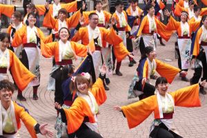 Theres under ett uppträdande på Hamamatsu Ganko Festival tidigare i år. En grupp dansare som utför den japanska dansen yosakoi. De bär alla dräkter i orange. Dräkterna har vida ärmar.