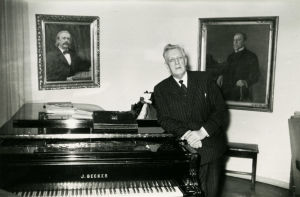 Ernst Linko rehtorin huoneessa, missä hän myös opetti. Ernst Linko nojaa flyygeliin Sibelius-Akatemian rehtorin huoneessa.