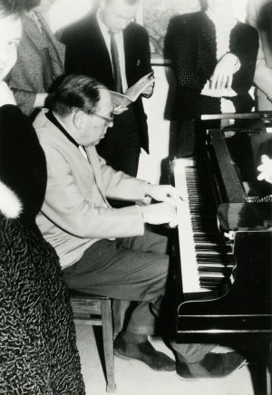 Gerald Moore soittaa opiskelijoiden ympäröimänä. Pianotaiteilja Gerald Moore soittaa opiskelijoiden ympäröimänä.