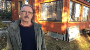 Tusbybon Jarmo Kyttänen tänker inte ge upp stuglivet, trots att han störs av flygbullret. Stugan ligger ungefär två kilometer från flygplatsen. Medelålders man står utanför en stuga i trä.