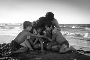 Roma, ohjaus Alfonso Cuarón. Lapset ja lastenhoitaja halaavat toisiaan meren rannalla. Kuva Alfonso Cuarónin elokuvasta Roma (2018).