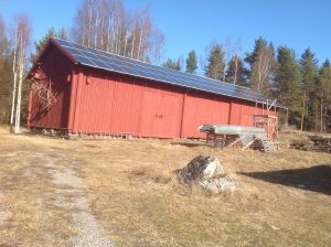 En röd lada med solpaneler på taket.