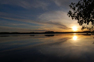 Aurinko laskee keltaisenaan suomalaiseen järvimaisemaan.