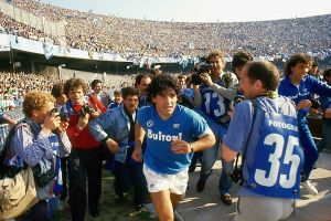 Maradona juoksee S.C.C. Napolin kotistadionin, Stadio San Paolon nurmelle. Diego Maradona juoksee S.C.C. Napolin kentälle ensimmäistä kertaa vuonna 1984 kuvaajien ympäröimänä.