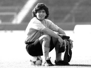 Jalkapalloilija Diego Maradona istuu pallon päällä vuonna 1989.