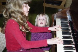 Saara soittaa mummin harmoonia, pikkusisko Suvi laulaa. Saara Aalto soittaa lapsena mummin harmoonia, pikkusisko Suvi laulaa