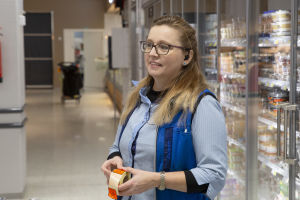 Enligt försäljare Maria Niinipalo har rödmärkta varor fått fler kunder att söka sig till S-butiken kvällstid. En kvinna i s-gruppens blå dräkt står i en butik och håller i en rulle med orange rea-lappar.