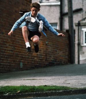 Billy Elliot (Jamie Bell). Billy Elliot (Jamie Bell) hyppäämässä ilmaan balettitossut kaulan ympäri kietaistuna.