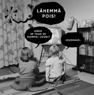 Kaksi lasta yrittää katsoa televisiota, vaikka Homspsi-Jouni häiriköi.