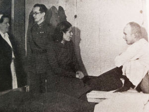 Sairaalavuoteisiin ilmestyi yllättäen lisää potilaita, kun kuultiin että Anna Mutanen on tulossa. Anna Mutanen istuu potilaan sängyn laidalla sotasairaalassa.