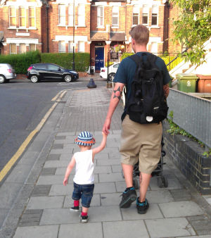 Petteri Pykäläinen kävelee käsi taaperoikäisen lapsen kädessä lontoolaiskadulla.
