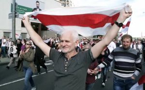 Ales Bialiatski. Ales Bialiatski går i tåg med människor omkring sig och håller upp den rödvita flaggan som används i demonstrationerna i Belarus.
