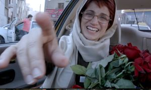 Nasrin Sotoudeh i Jafar Panahis film "Taxi Téhéran". Nasrin Sotoudeh i baksätet på en bil med en bukett röda rosor. Bilden är från Jafar Panahi's film "Taxi Téhéran".