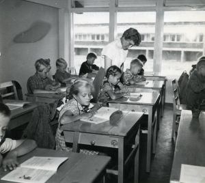 Opettaja ja koululaisia luokkahuoneessa Espoon Tapiolassa. Mustavalkoinen kuva peruskoulusta.