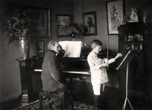 Kapellimestari Robert Kajanus opettaa poikaansa Kai Kajanusta viulunsoitossa vuonna 1915.
