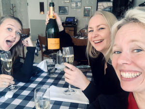 Andrea tillsammans med regissören Zaida Bergroth och Alma Pöysti som gör rollen som Tove Jansson. Tre glada kvinnor sitter vid ett bord och skålar i champagne.