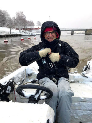 Fritjof sitter i båten på väg på vinterutflykt till stugan på Tvärnö i Vasa skärgård. Fritjof sitter i en snöig öppen båt på väg ut från hamnen. Det snöar ute och man ser snöflingorna yra iluften. Han har svart jacka med huva uppdragen över huvudet.